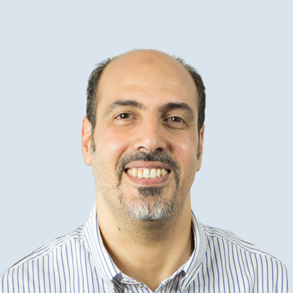 Elmostafa is a white skinned male . He has a mixture of black and grey hair. He wears a striped blue and white shirt and is pictured smiling against a blue-grey background.
